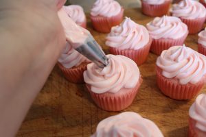 Piping frosting on to pink champagne cupcakes 