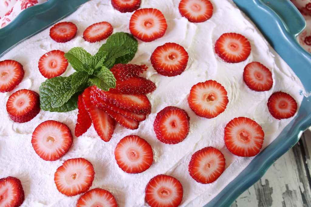 Strawberry Ice Box cake in a blue baking dish with strawberries on top