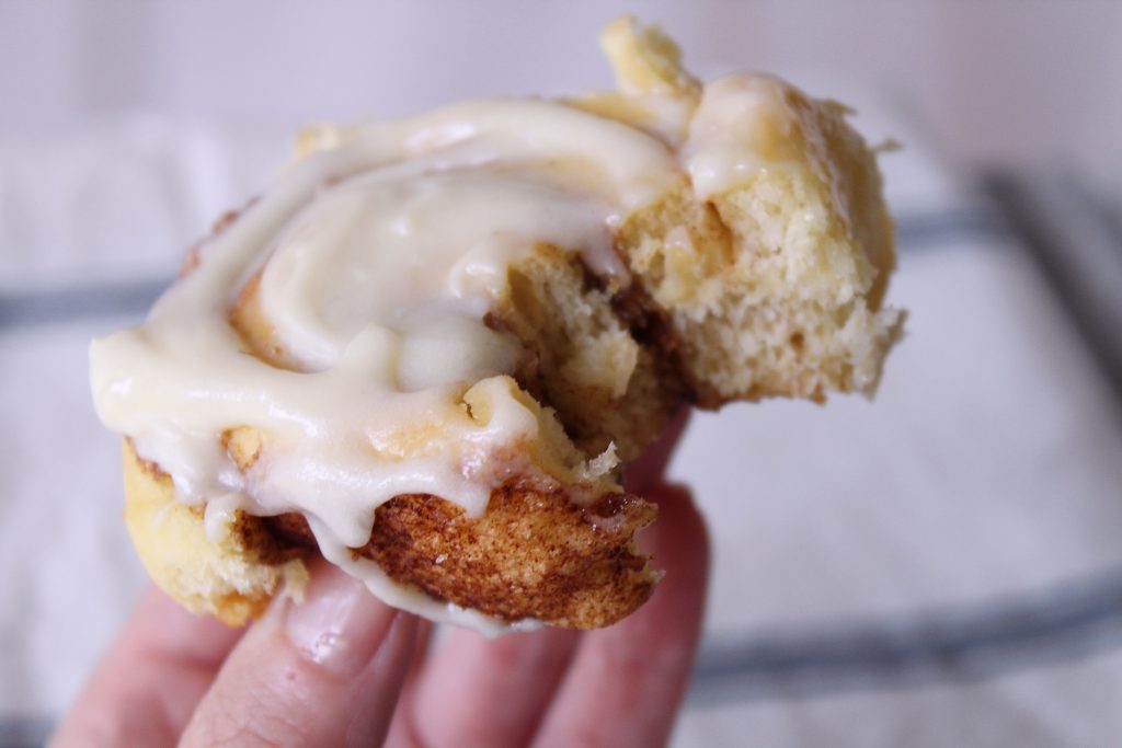 a cake mix cinnamon roll with cream cheese frosting with a bite taken out of it. 