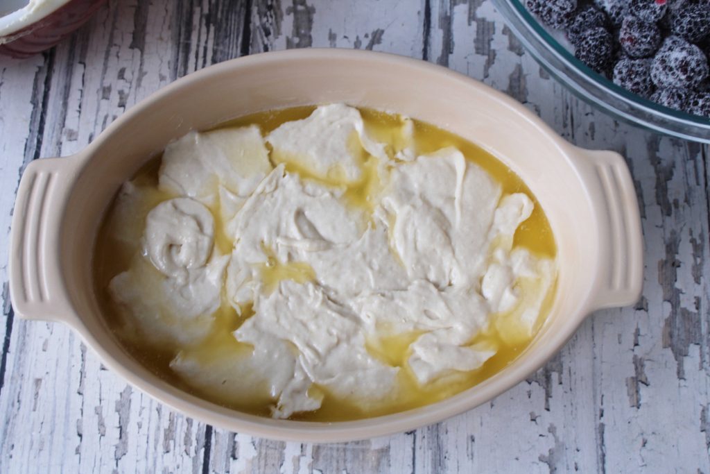 Cobbler batter poured into the dish with butter 