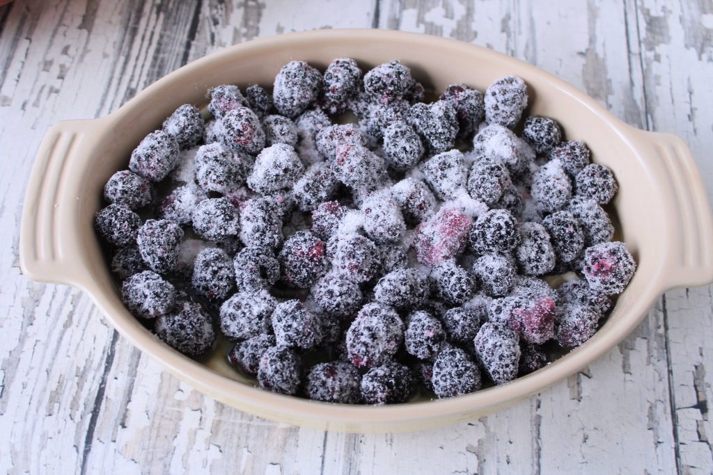 Blackberries and sugar on top of the blackberry cobbler bater 