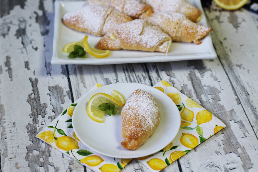 Lemon Cream Cheese Crescents  on a white plate with a lemon wedge