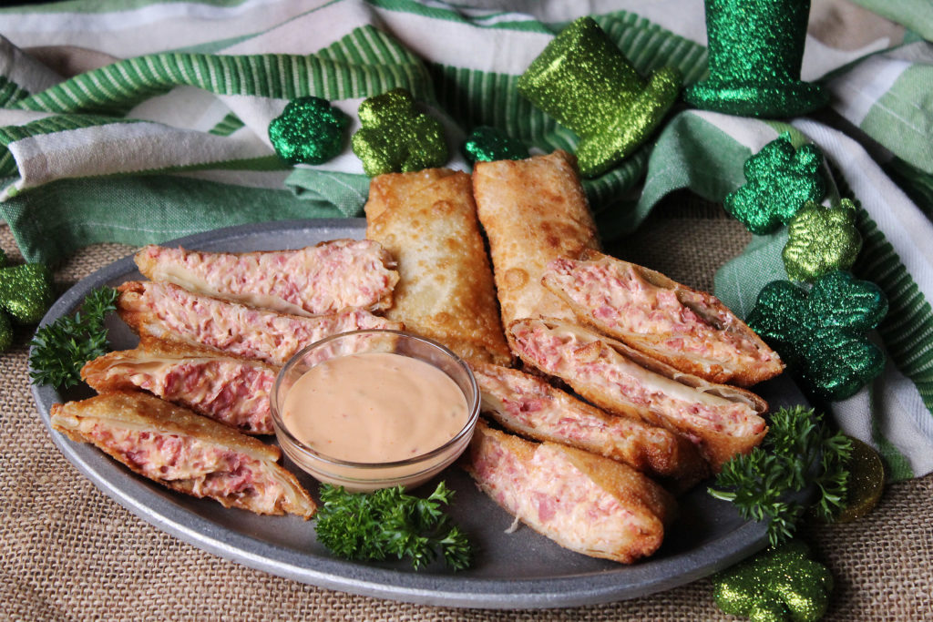 Reuben Egg Rolls cut and whole on a platter with dipping sauce