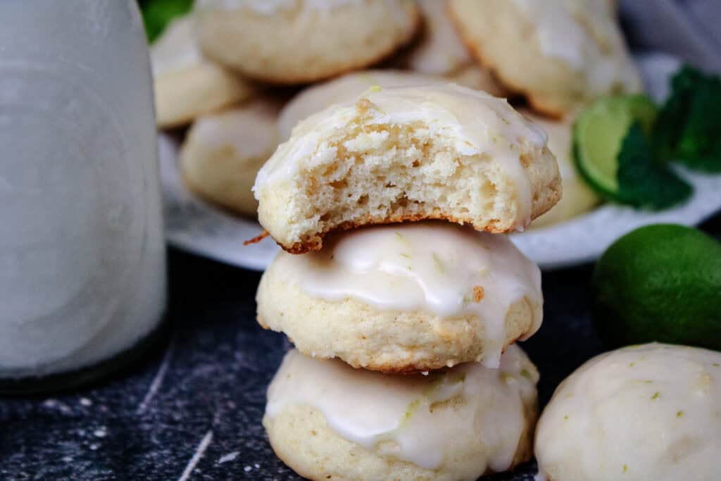 A bite taken out of a key lime ricotta cookie showing the fluffy inside . 