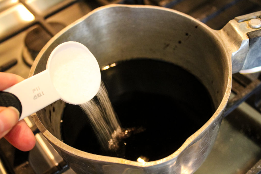 Adding sugar to a pot of balsamic vinegar to make the glaze