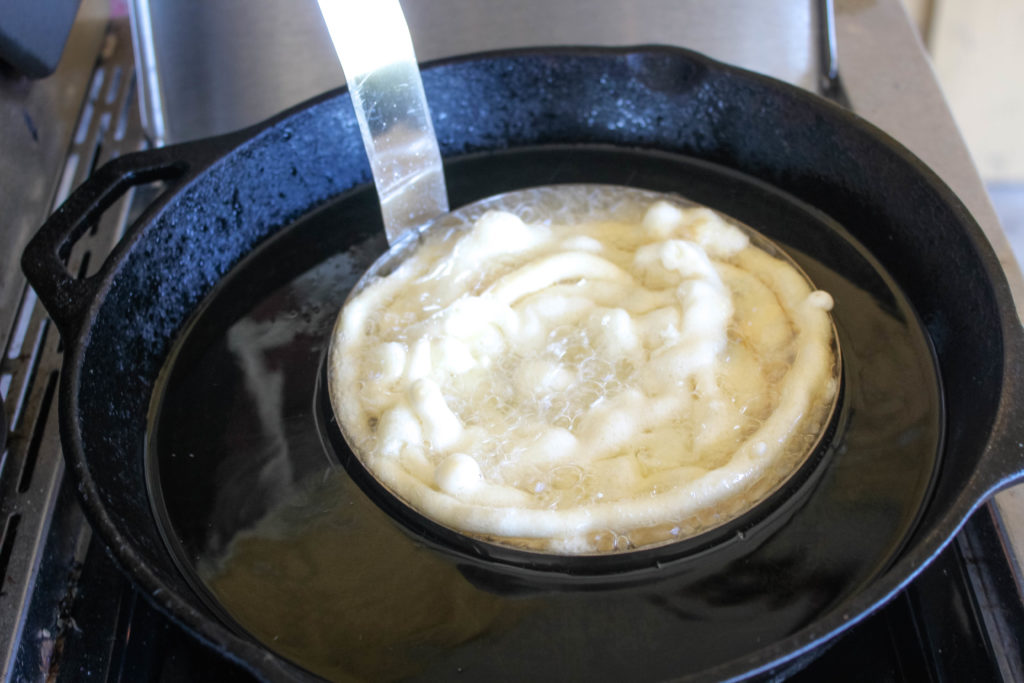 Funnell cake frying in a oil with a mold