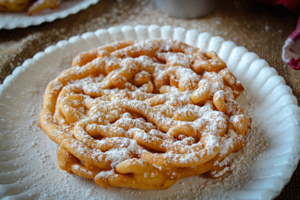 Fair Funnel Cake on a paper plate dusted with powdered sugar. 