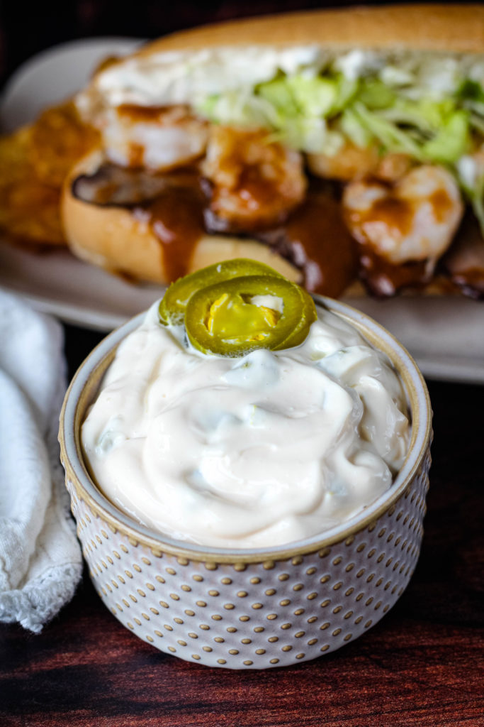 Jalapeno Mayo in a beige serving bowl with two jalapenos on top. 