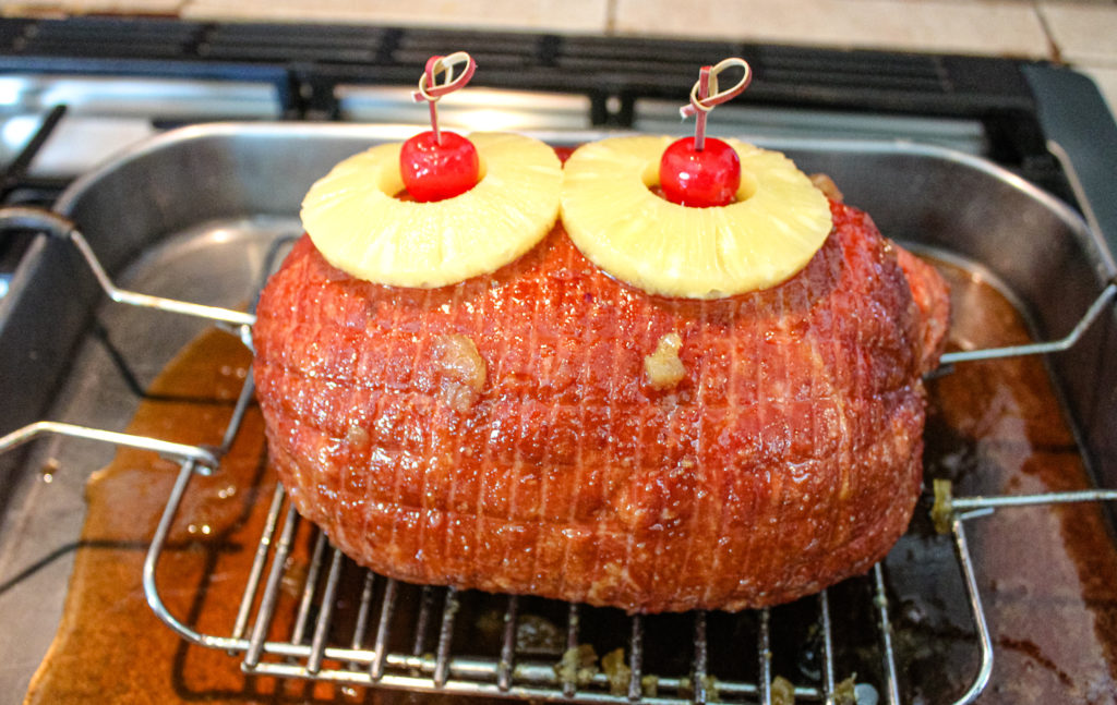 Ham in a baking pan with glaze poured over it. 