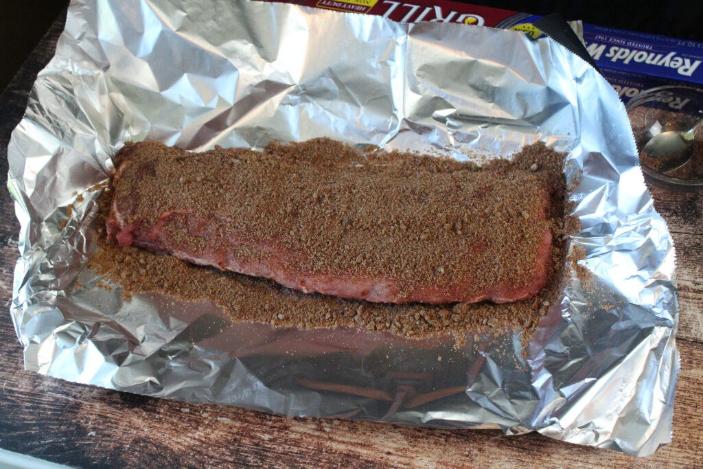 uncooked ribs in foil with seasoning spread on thwm