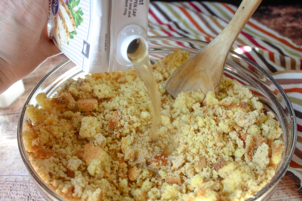 pouring chicken broth over the cornbread