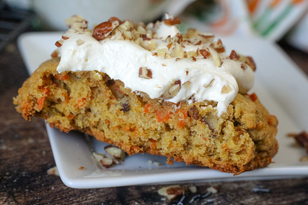 Crumbl Carrot Cake Cookies on a white plate with a bite taken out showing the inside