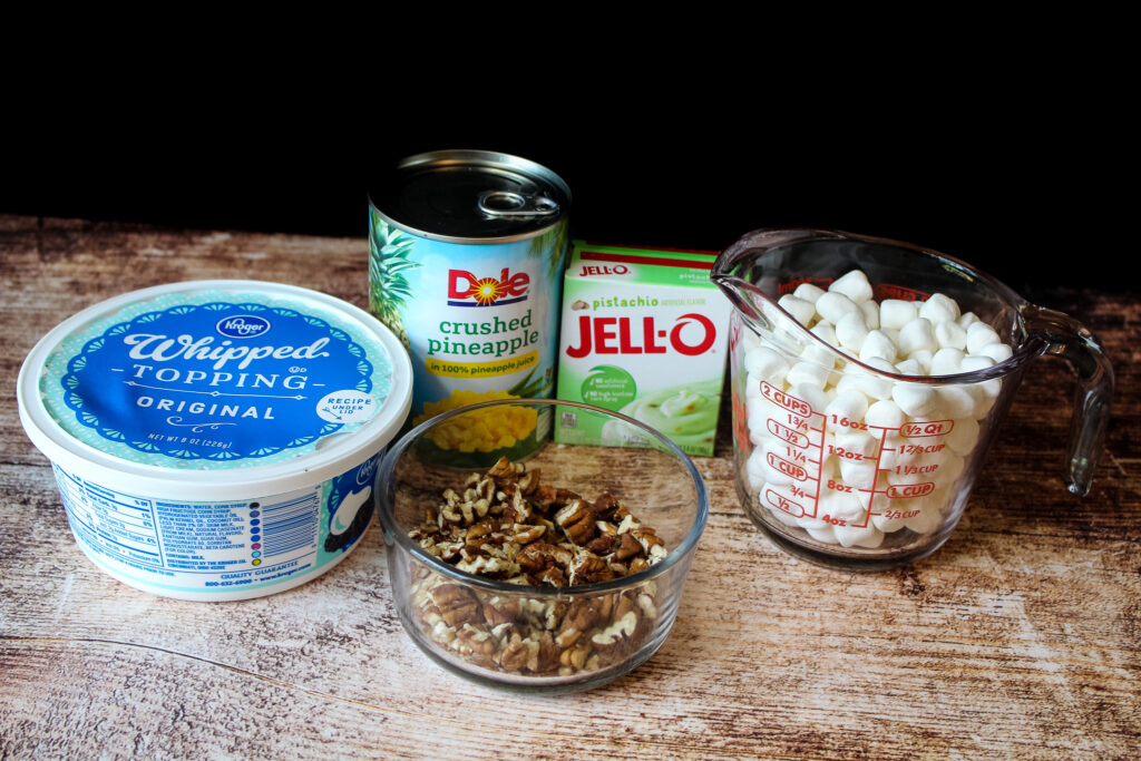 Whipped topping , chopped pecans , a can of crushed pineapple , pistachio pudding and a cup of marshmallows 