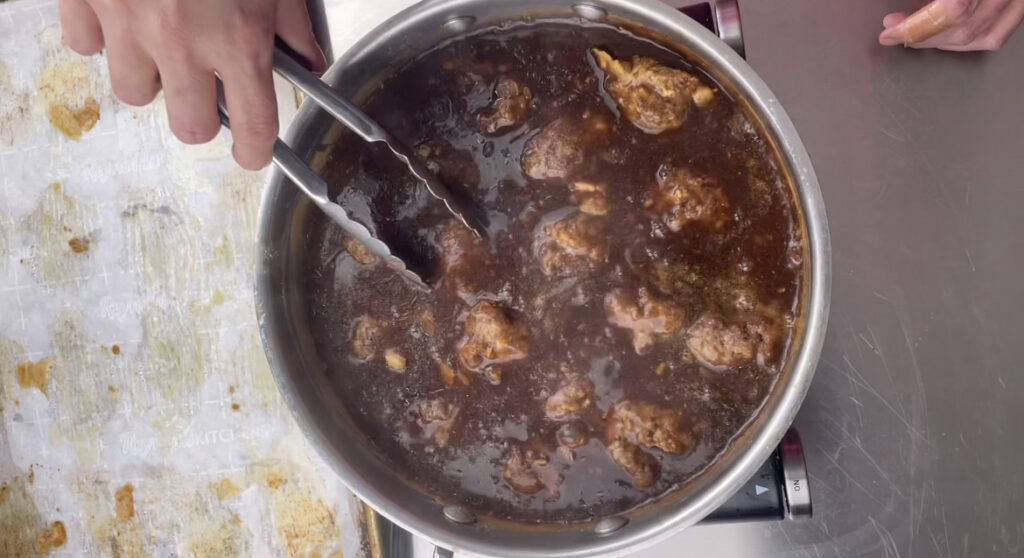 Cooked meatballs going into the brown gravy