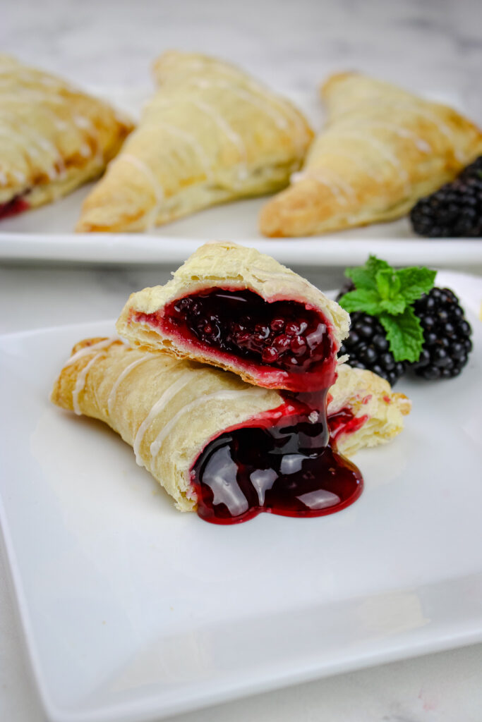 Blackberry Turnovers cut in half on a white plate . 