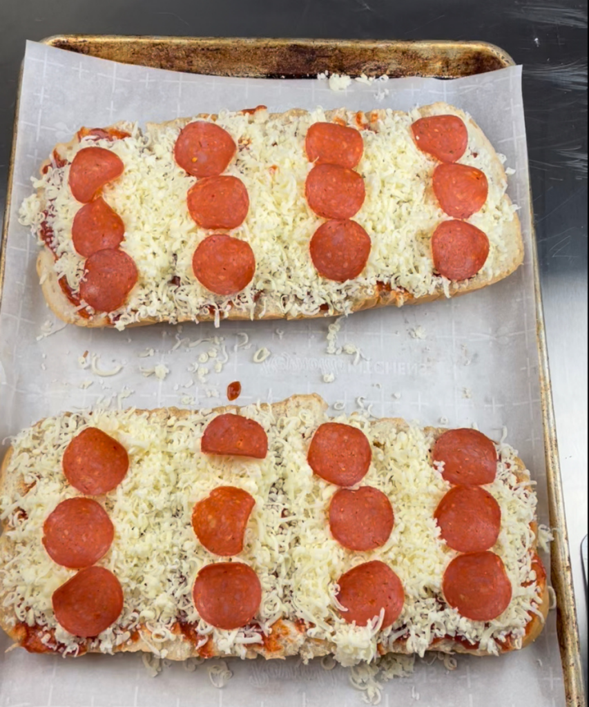 The cheese and pepperoni added to make French bread pizza 
