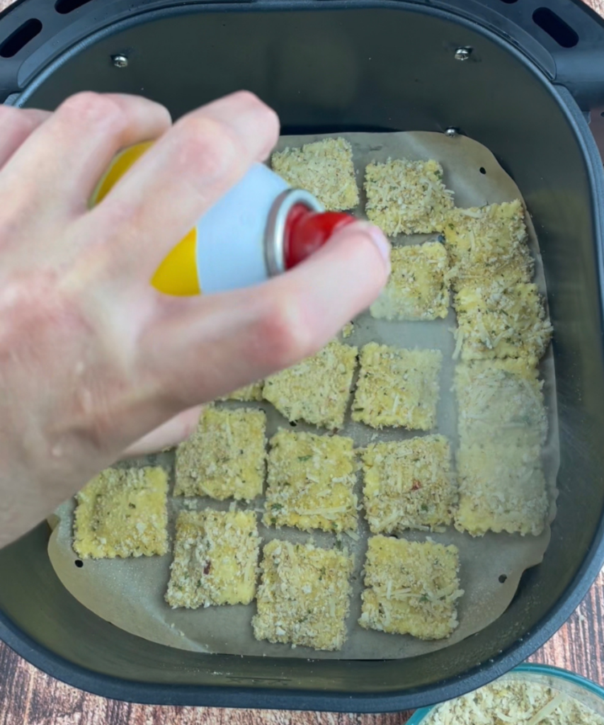 Spritzing the air fryer ravioli with cooking spray
