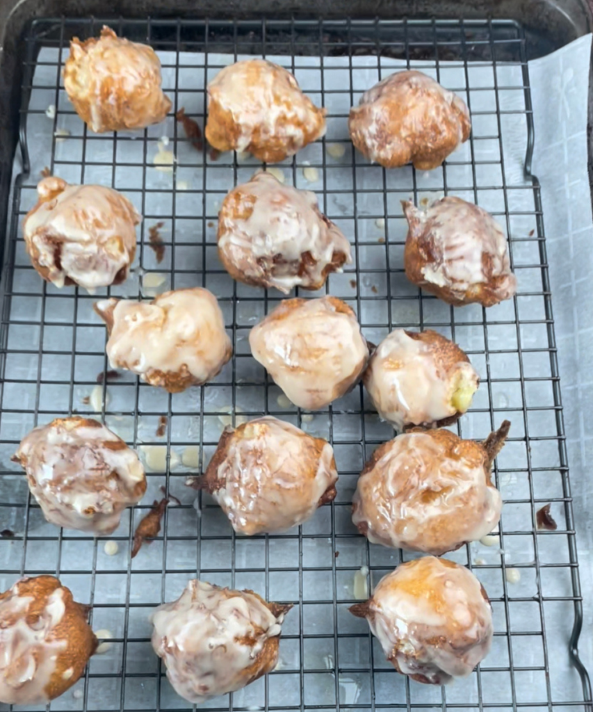 Apple fritters on a cooling rack drizzled with glaze 