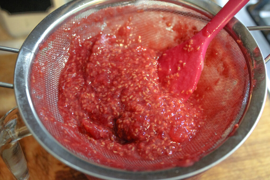 Straining the seeds from the raspberry sauce 