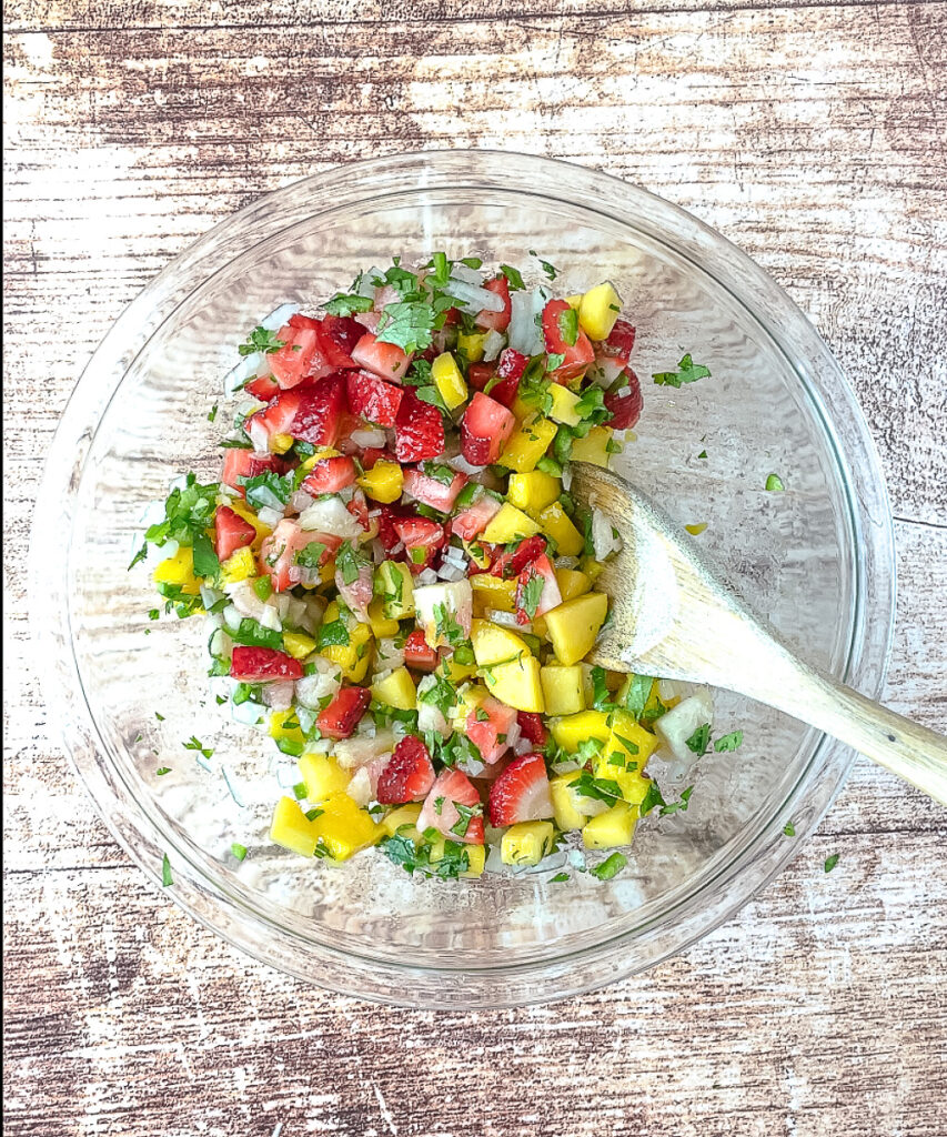 Fruit salsa tossed together in a clear mixing bowl