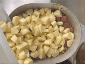 Adding the peeled and cubed potatoes to the pot for Cajun Sausage Potato soup