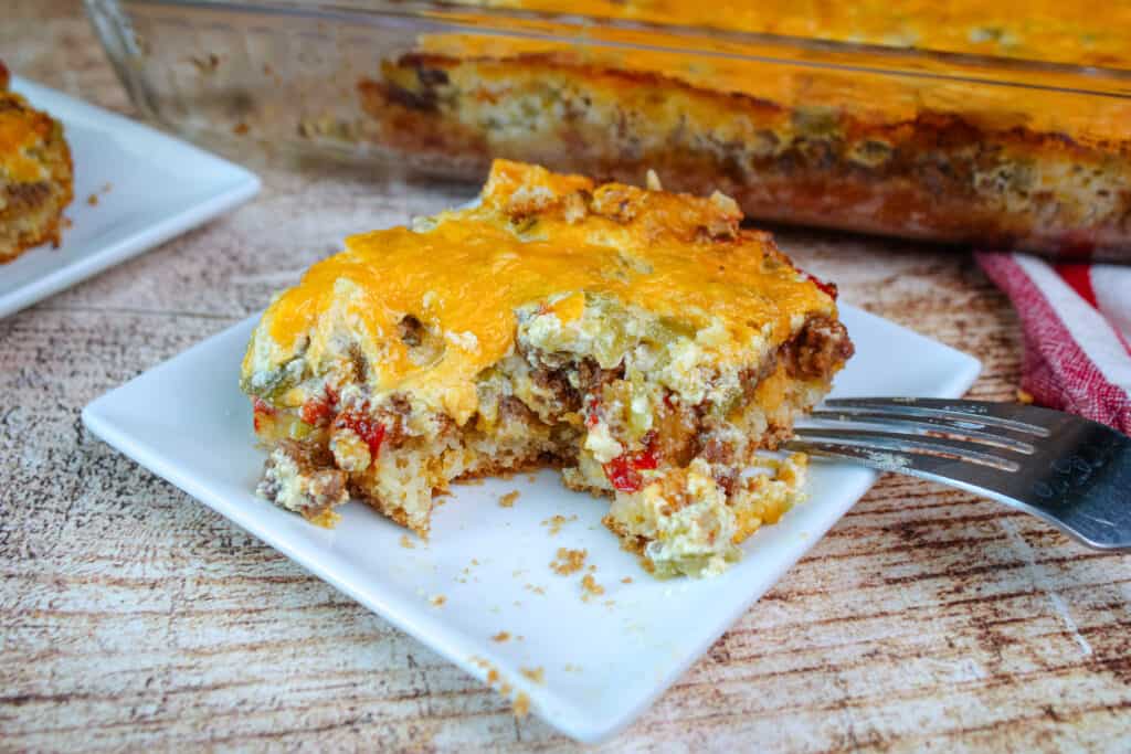 A square piece of cattle drive casserole on a small white plate with a bite taken out of it