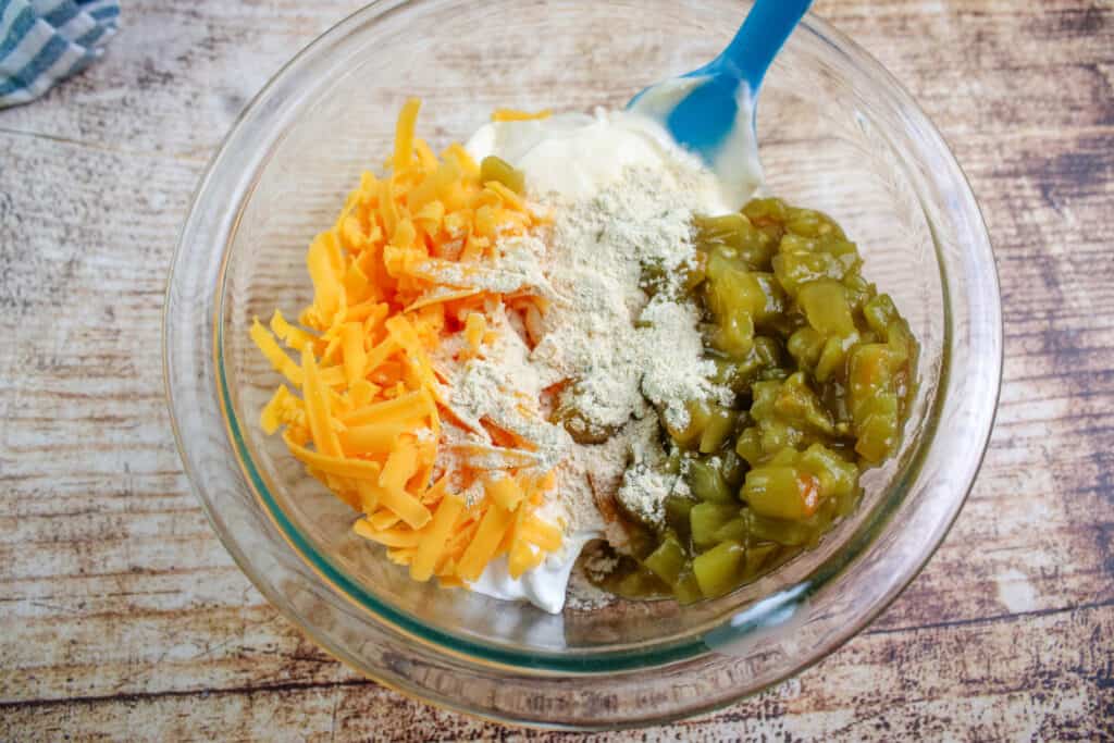 Mixing together the mayo , sour cream , cheese , chopped chiles and garlic for cattle drive casserole