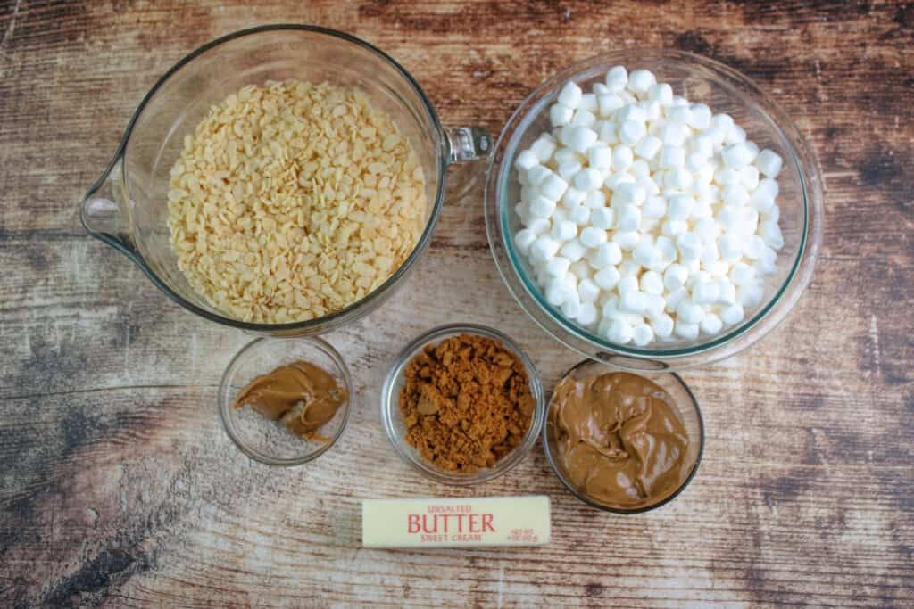 The ingredients in a bowl for cookie butter rice krispie treats all in bowls -rice cereal , cookie butter , butter , mini marshmallows, and chopped cookies
