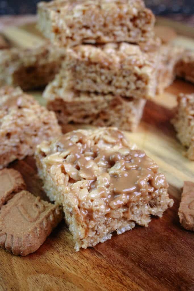 Cookie butter rice Krispie treats cut into squares on a cutting board with chunks of Biscoff cookies