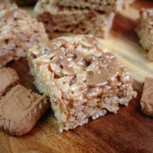 Cookie butter rice Krispie treats cut into squares on a cutting board with chunks of Biscoff cookies