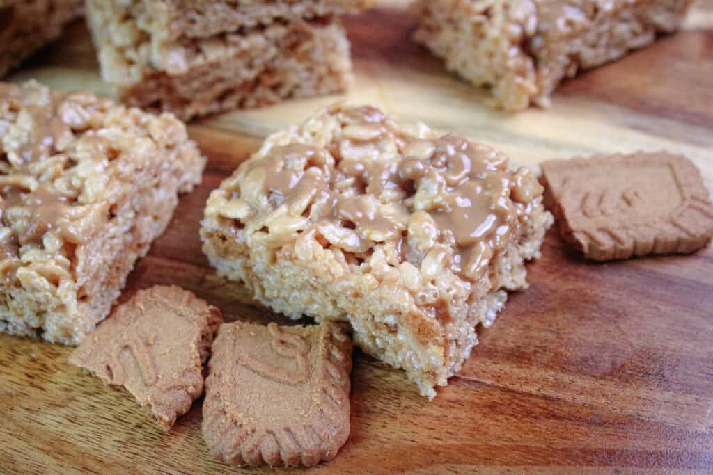 Cookie butter rice Krispie treats cut into squares on a cutting board with chunks of Biscoff cookies