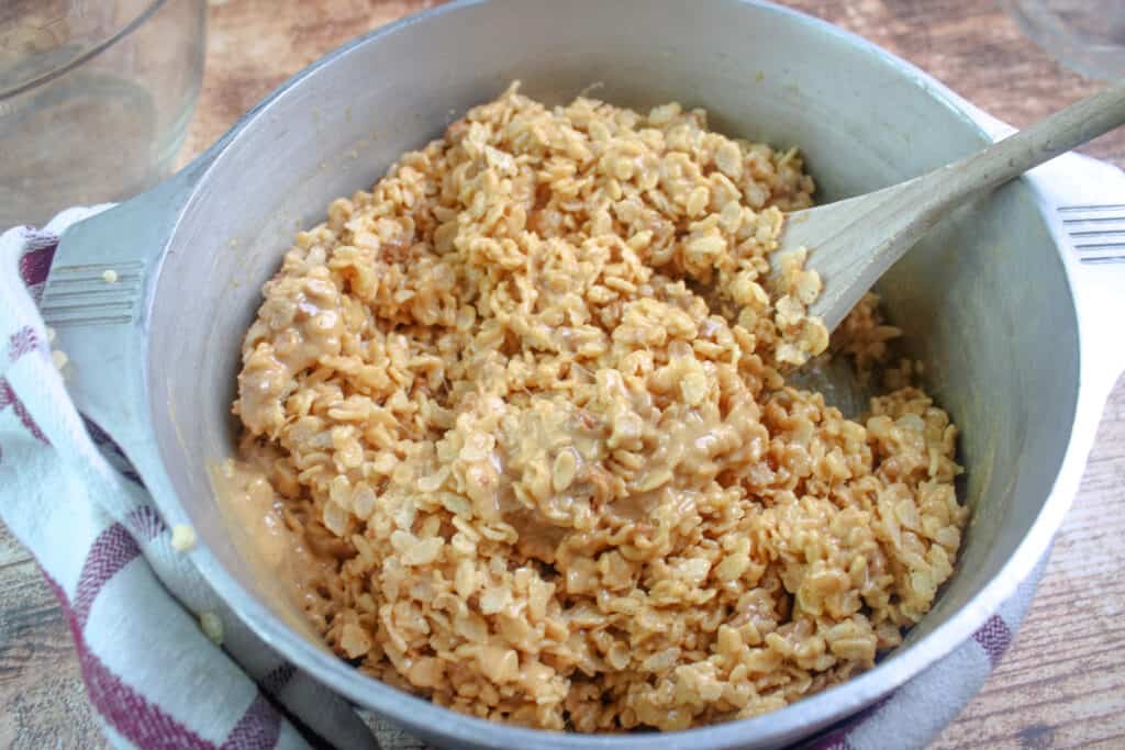 Rice crisp cereal added to the melted mixture in a large pot for cookie butter rice krispie treats