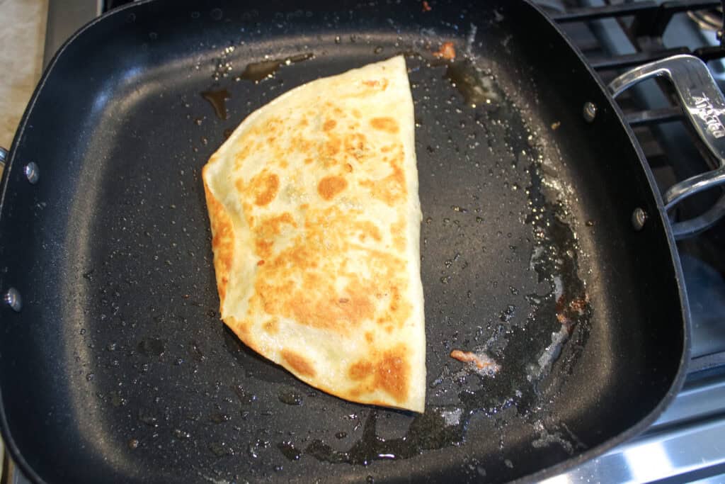 Flipping the steak quesadillas over and allowing the other side to cook