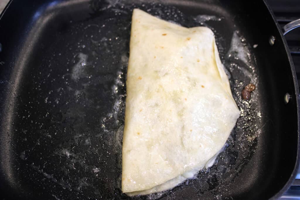Leftover steak quesadilla cooking on one side