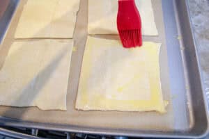 Egg wash brushed around the edges of one of the squares of puff pastry for turnovers