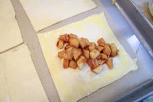 Apple filling placed int he center of one of the squares of puff pastry for apple turnovers