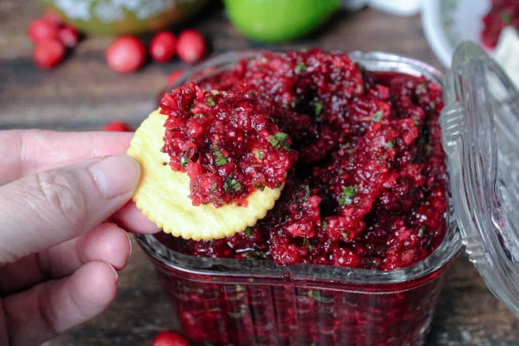 Cranberry jalapeno relish being served on a round cracker