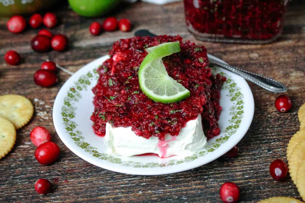 Cranberry jalapeno relish served over a block of cream cheese on a round plate