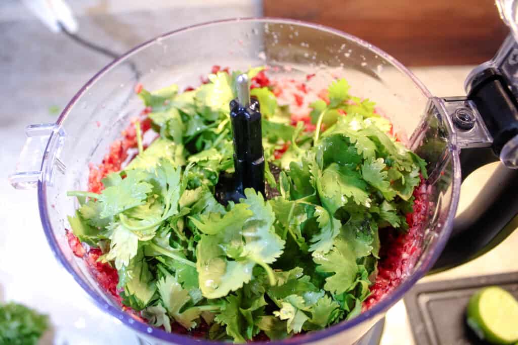 Adding cilantro and lime to the food processor for Cranberry Jalapeno Relish