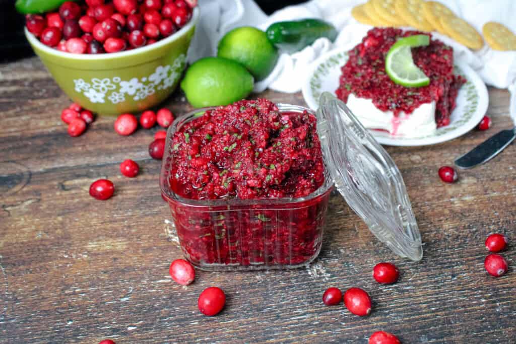 Cranberry jalapeno relish in a small square glass dish surrounded by fresh cranberries