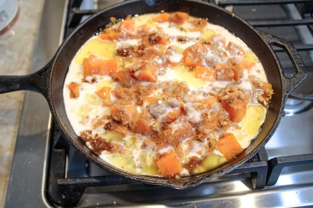 The cobbler crust poured over the cooked sweet potatoes in the cast iron skillet 