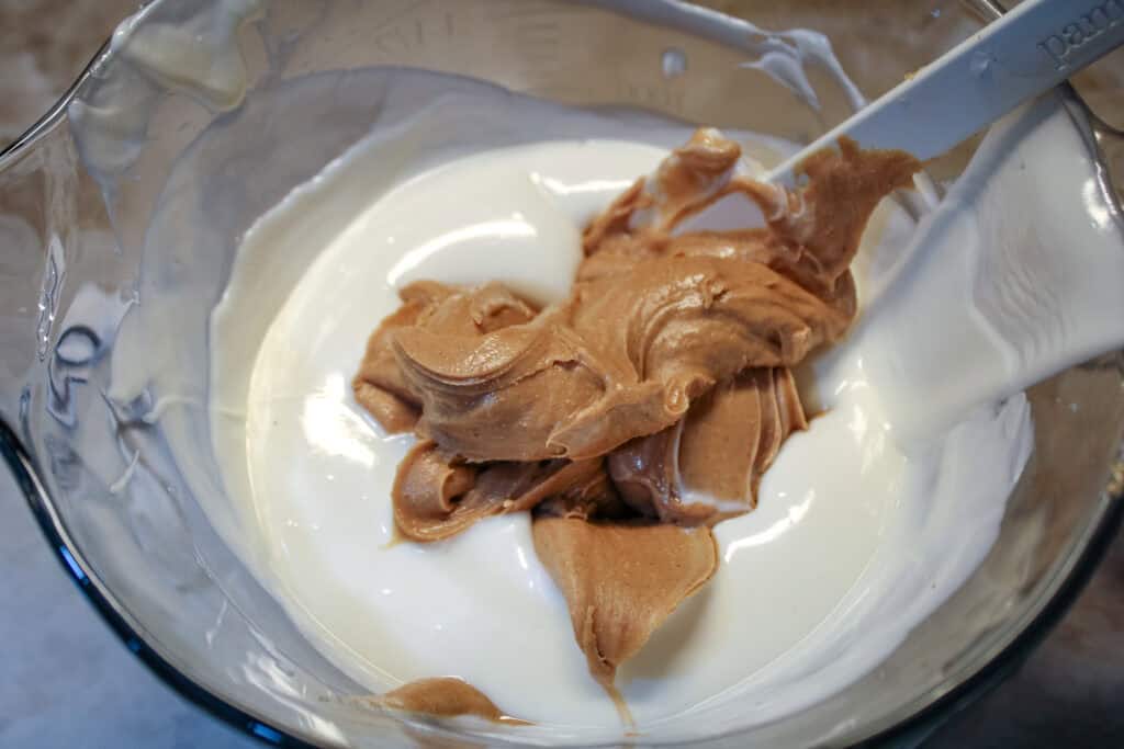 Melted vanilla almond bark in a large bowl with peanut butter added 