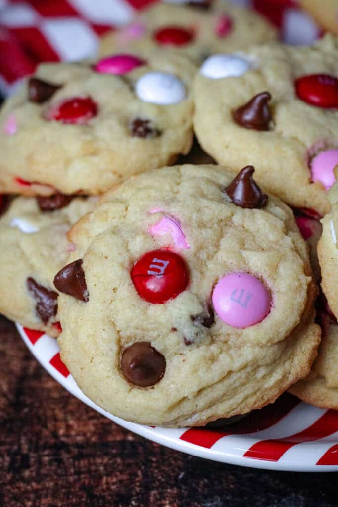 A close up of a Valentine M&M cookie on a red and white stripped plate . 