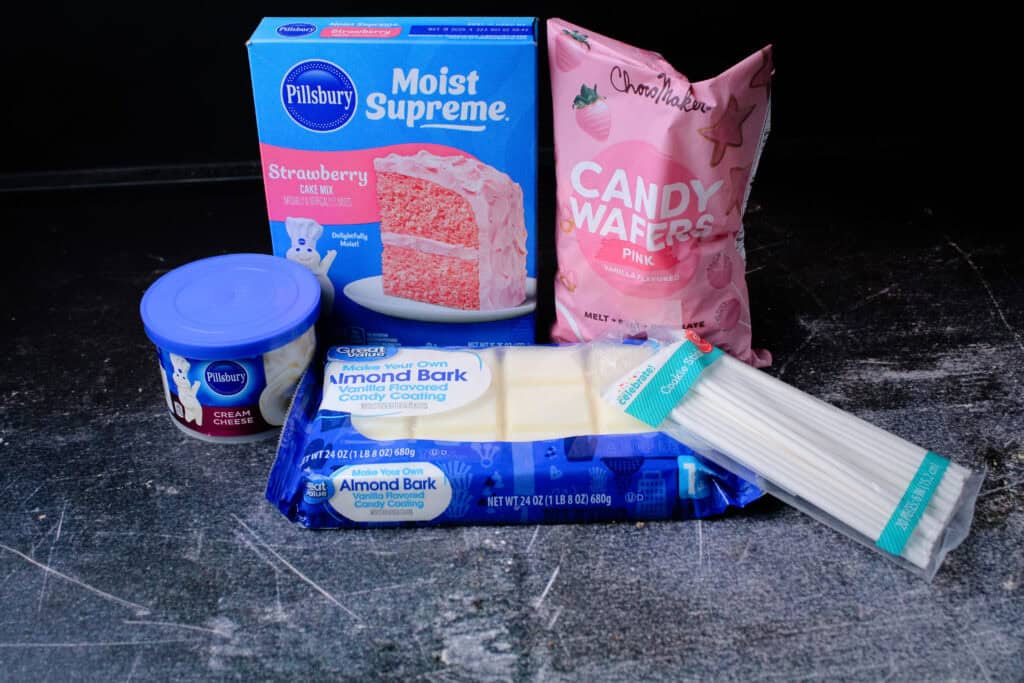 Strawberry cake mix , pink candy coating , cream cheese icing , vanilla almond bark , cake pop sticks .