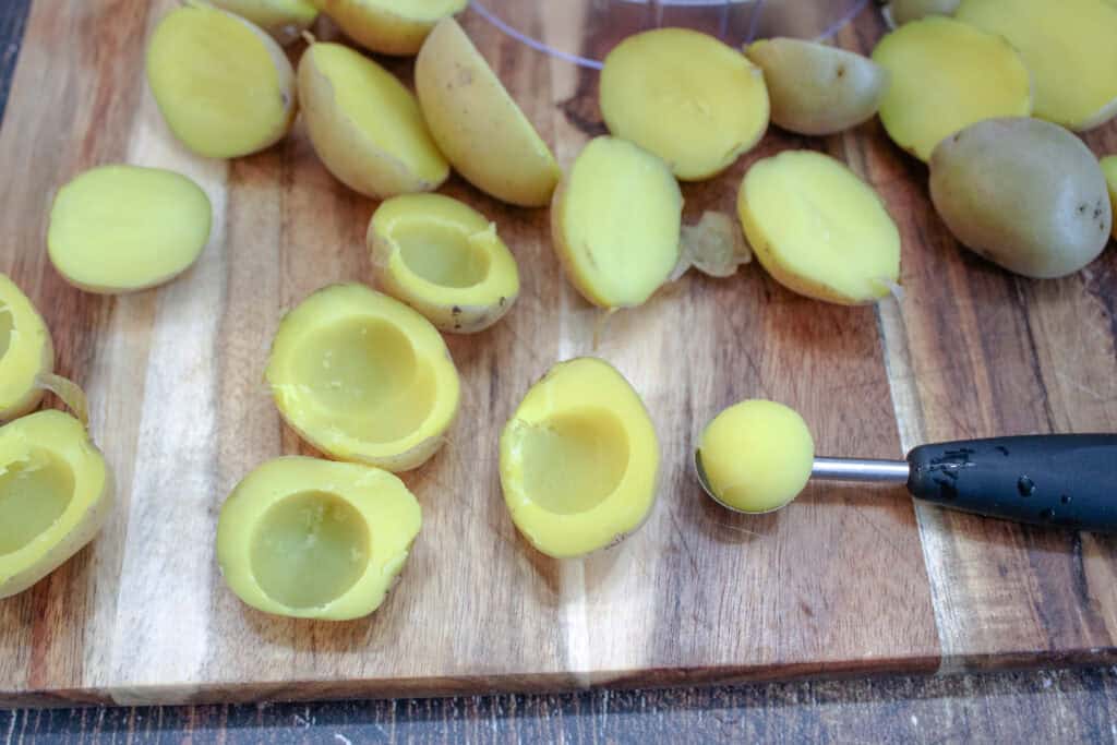 Scooping the flesh of the potato out with a melon baller 