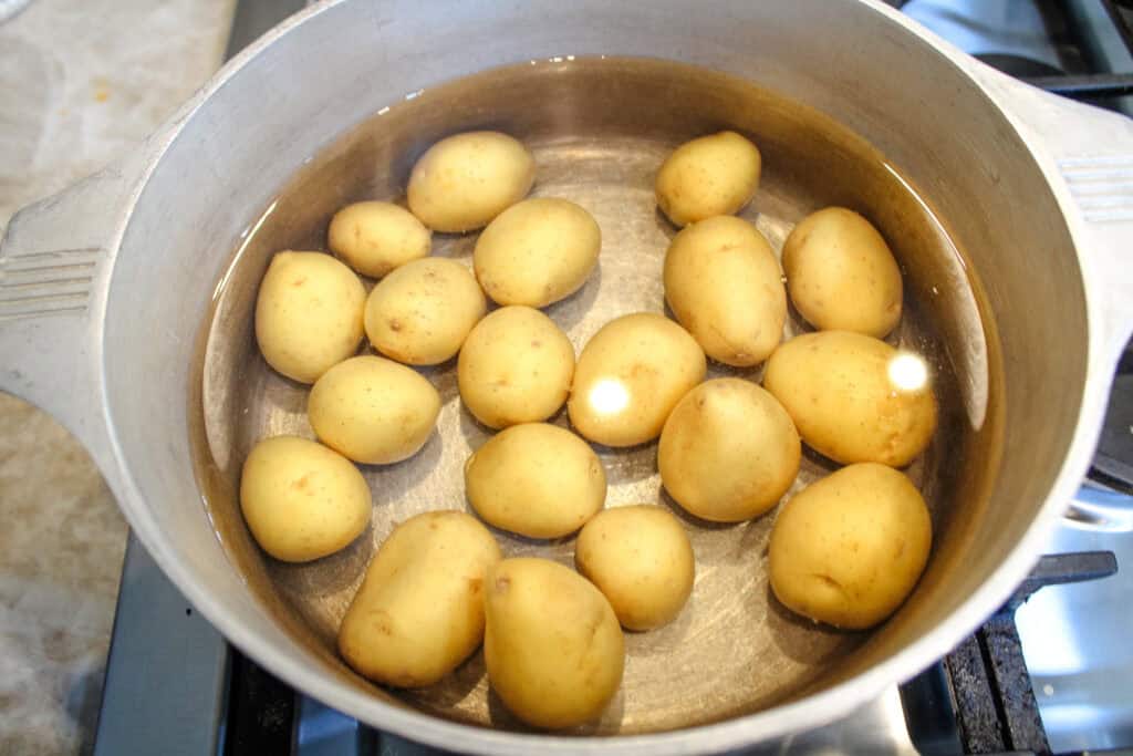 Baby potatoes in a pot covered with water . 