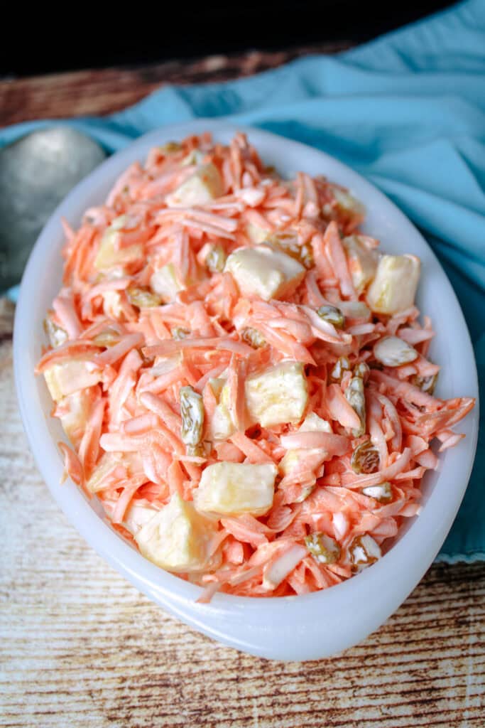 Old Fashioned carrot salad in a white vintage dish with a blue napkin next to it 