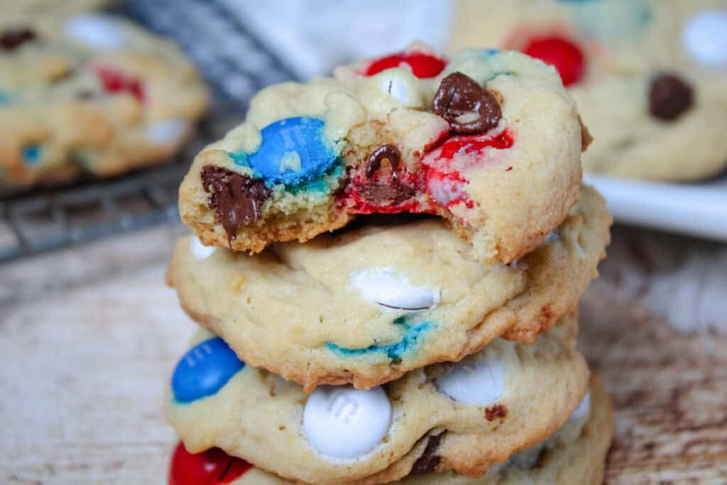 Stack of chewy Patriotic M&M Cookies with the top cookie showing a gooey chocolate center and vibrant red and blue M&M’s.
