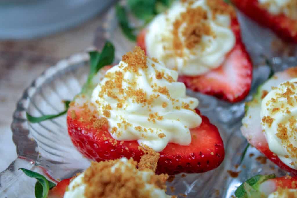 Strawberry cheesecake bites made with fresh strawberries, cheesecake filling, and cookie crumbs arranged on a serving platter.