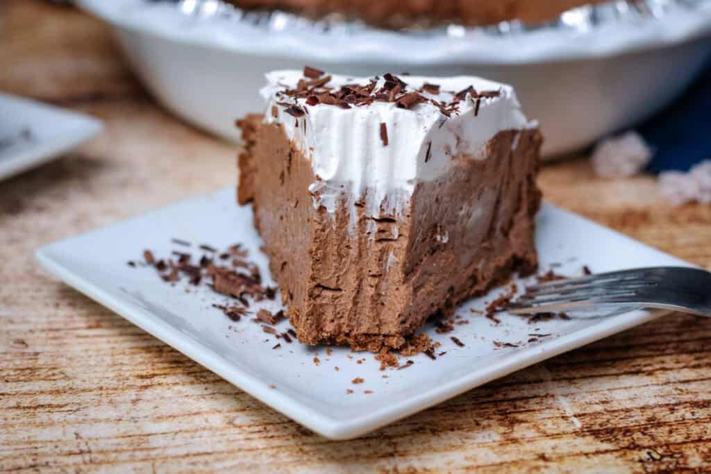 Close up slice of easy chocolate cream pie with layers of creamy chocolate filling and whipped topping with a bite taken out 